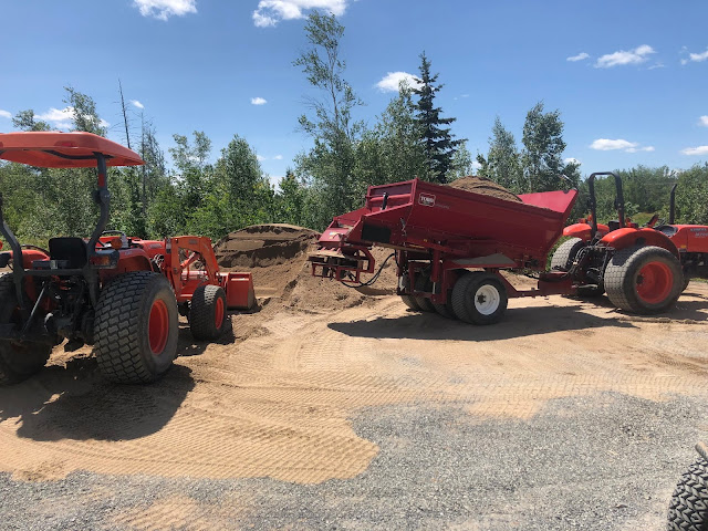 Tractors dumping sand.